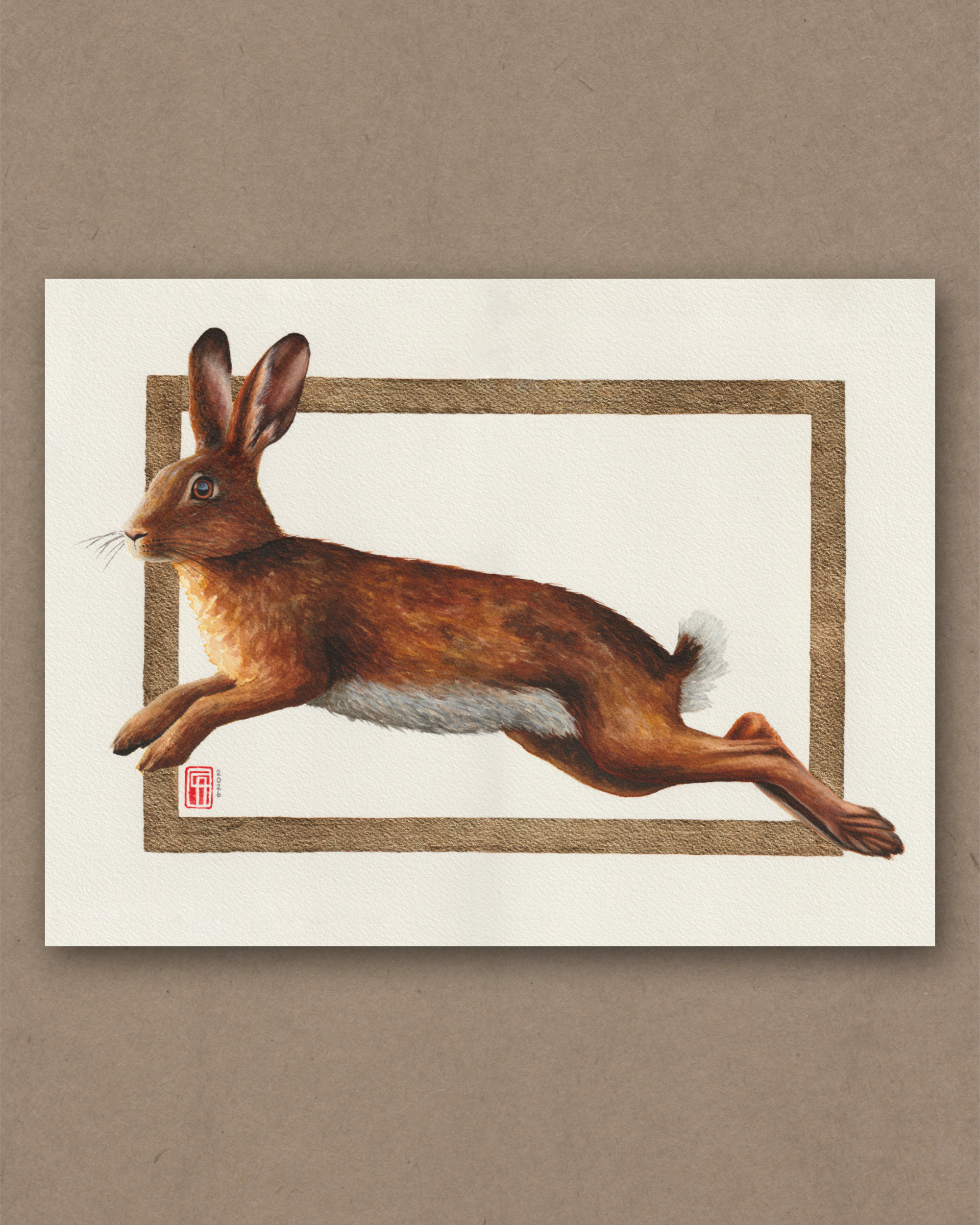 Aquarellgemälde eines Hasen im Sprung mit dem Titel "Golden Leap". Das Gemälde hat einen Rahmen aus Blattmessing (Schlagmetall, Goldimitat).